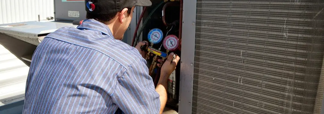 HVAC technician servicing a condenser unit in Marshfield