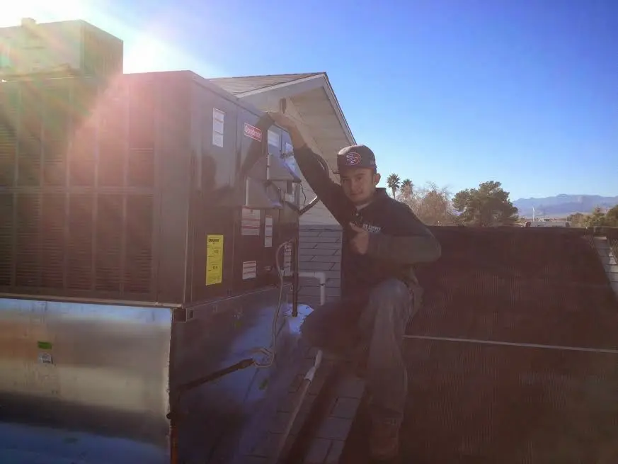 HVAC technician performing Heat Pump Repair on a rooftop unit in Marshfield